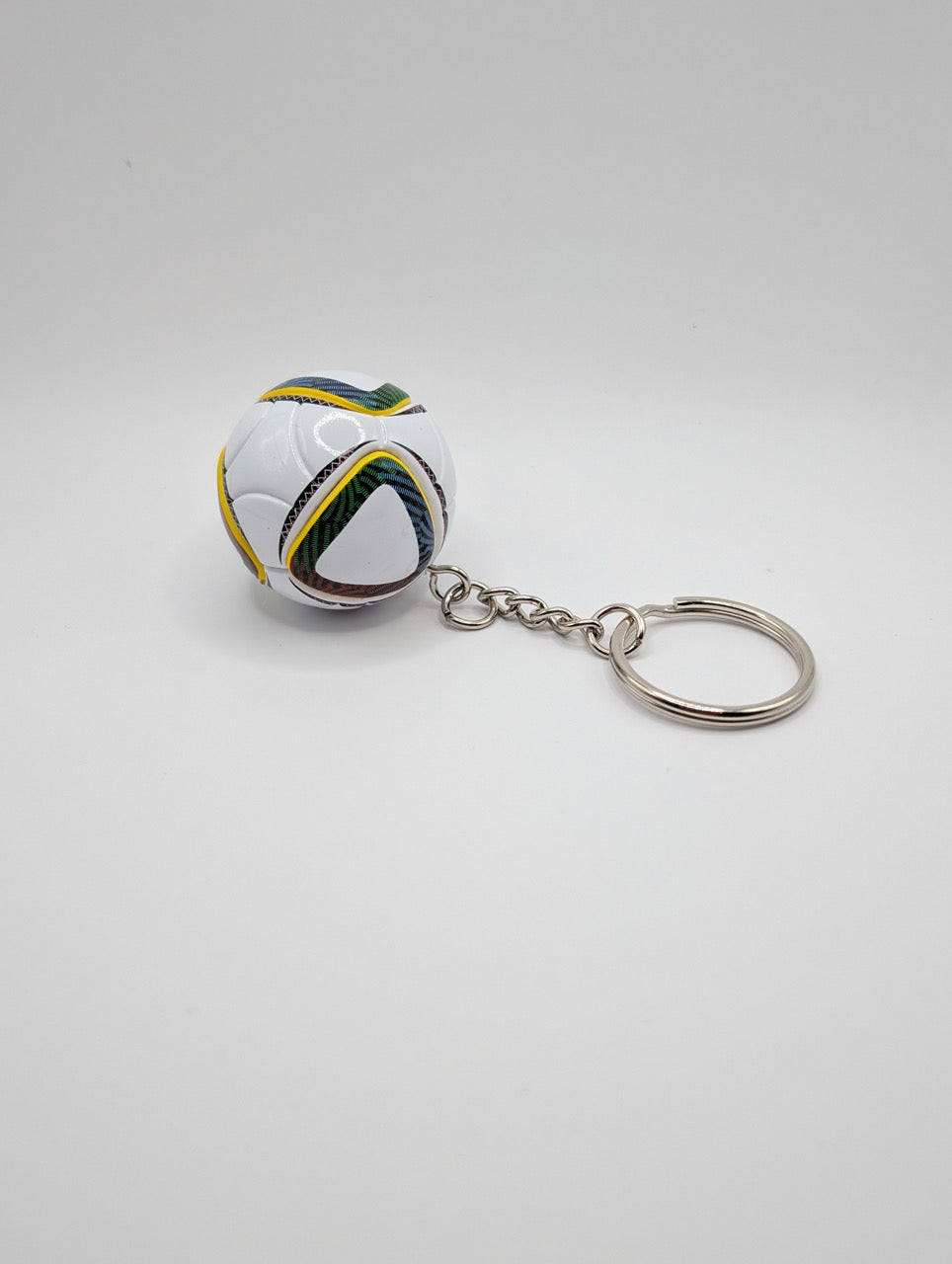 Keychain shaped like a soccer ball with Brazil flag colors on a white background
