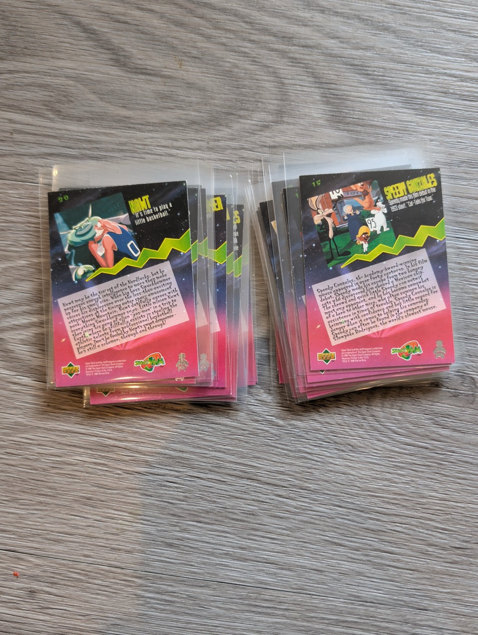 Collection of trading cards in clear plastic sleeves on a wooden surface